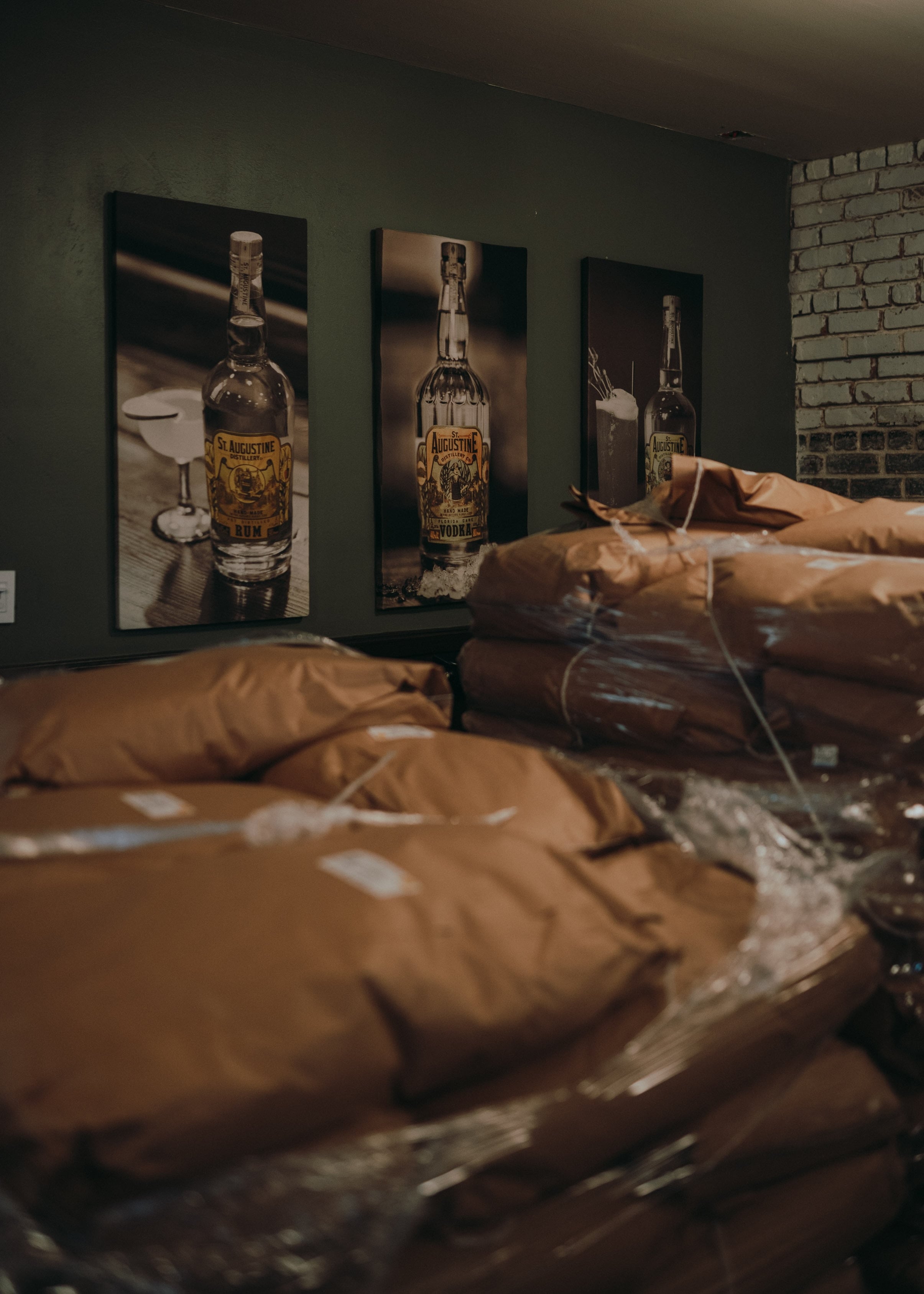 Gallery space with wrapped sculptures and whisky bottles on display